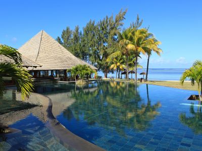 Pool des Heritage Awali auf Mauritius, mit Aussicht auf Strand und Meer.