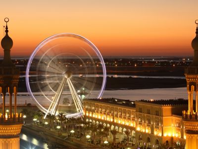 Die Flanierpromenade Al Qasba mit dem 60 Meter hohen Riesenrad Eye of the Emirates bei Abend.