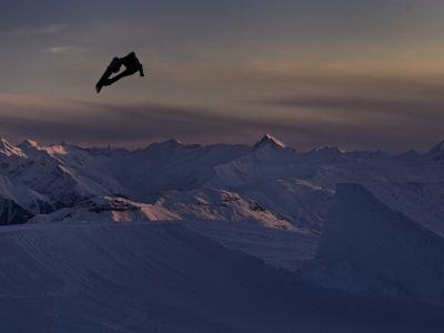 Ein Snowboarder nutzt die Freestyle-Pisten von Laax auch noch bei Dämmerung. Danach geht es vielleicht auf eine der Apres-Ski-Partys...