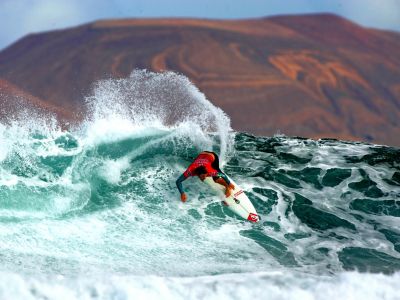 Surf-Profi Nic Muscroft beim „Islas Canarias Santa Pro 2009“ am Strand von San Juan auf Lanzarote – im Hintergrund die Nachbarinsel La Graciosa.